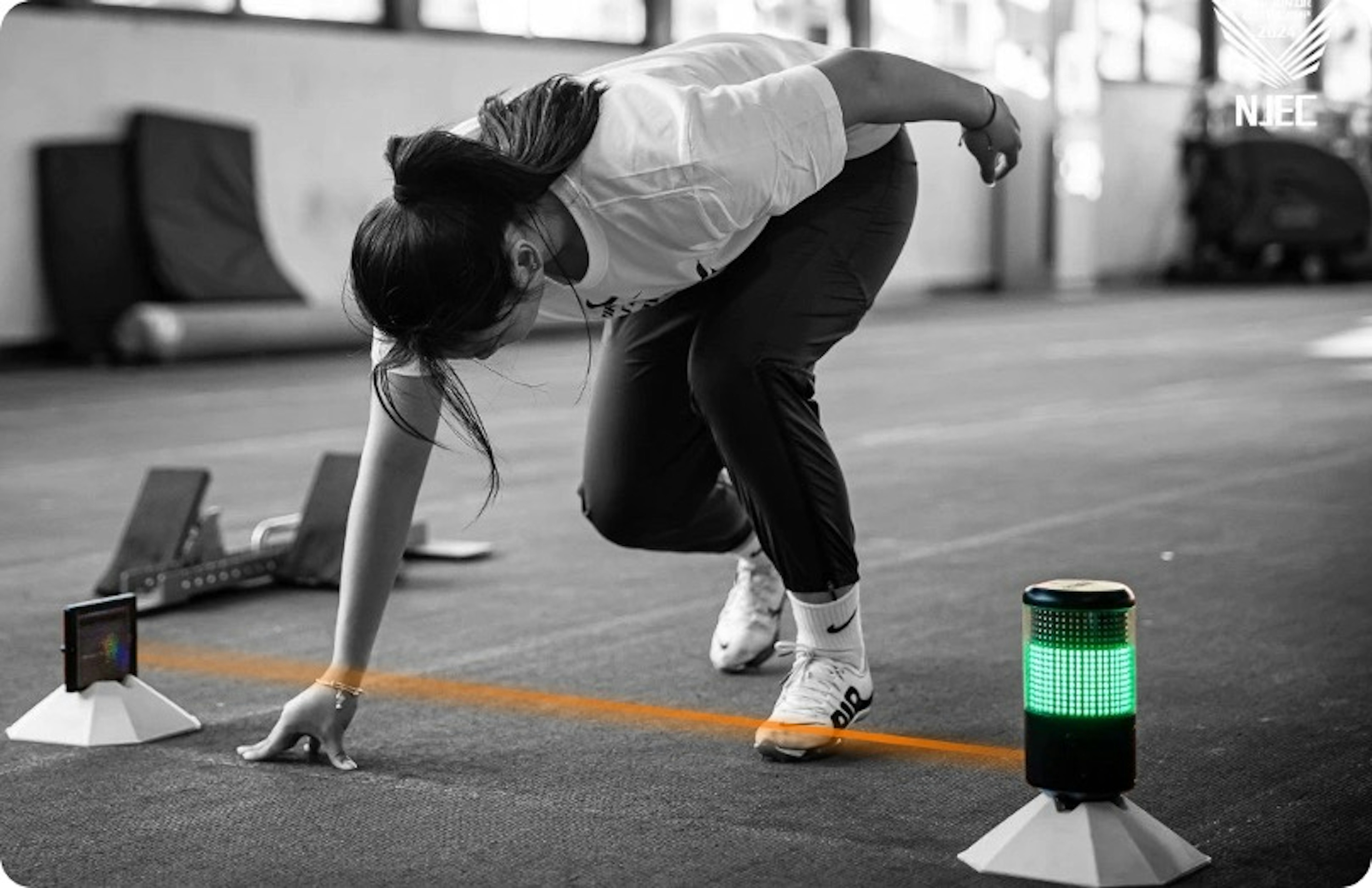 Athlete in three-point stance just before a speed assessment with superimposed infrared beam aligned with SmartSpeed reflector. 